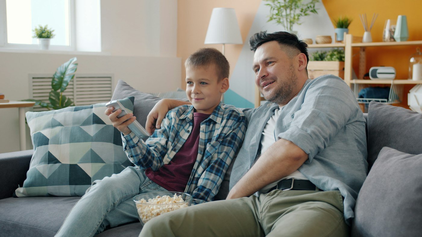 Father and son watching TV together on the couch